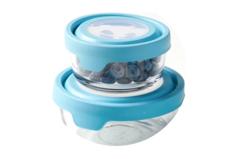 Two stacked Anchor Hocking TrueSeal round glass food storage containers with blue lids