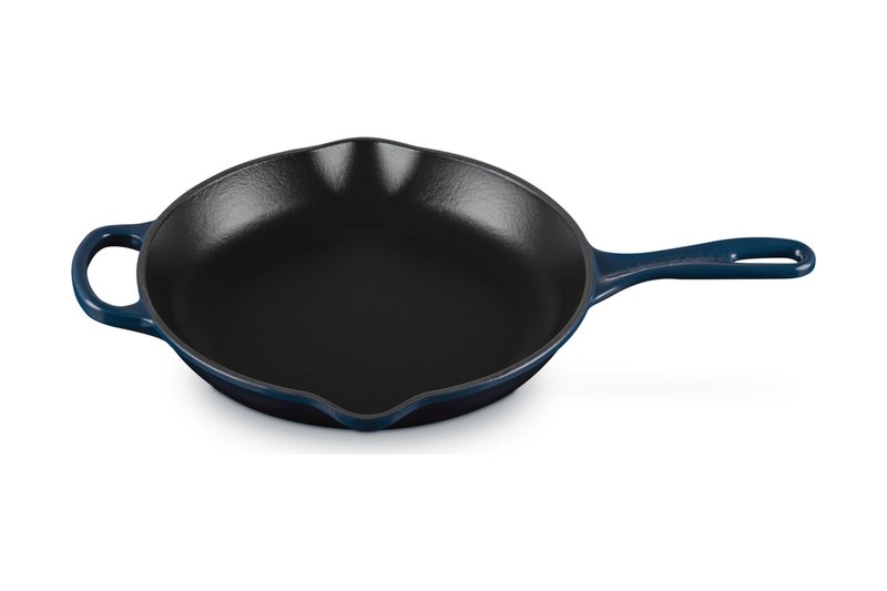 Le Creuset Signature cast iron round skillet in navy with a black enamel interior, a long handle and a helper handle